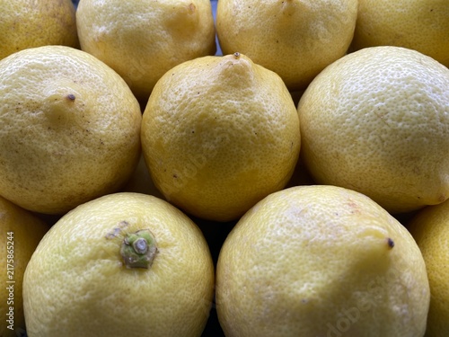 Fotografía Fresh organic yellow lemons in a close-up heap, showing textured citrus peel and vibrant natural color, perfect for healthy food concepts and culinary backgrounds