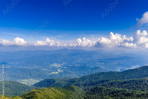 Aerial view of layered mountain ranges under massive cumulus clouds