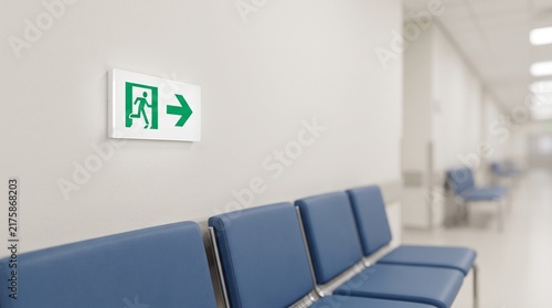 Emergency exit sign hangs on a wall hospital corridor