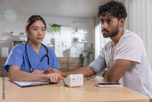 Cuadro en lienzo Healthcare professional measuring male patient blood pressure during medical checkup, monitoring vital signs while recording results for preventive care, health assessment, patient wellness