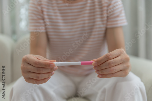 Foto Close-up of woman holding pregnancy test at home, representing pregnancy testing, reproductive health, family planning, fertility, uncertainty, waiting for an important personal result