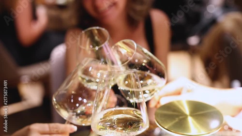 Guests celebrate and raise glasses with beverages, toasting and cheering with alcohol glasses with wine and champagne in a restaurant on corporate christmas birthday party event or wedding celebration