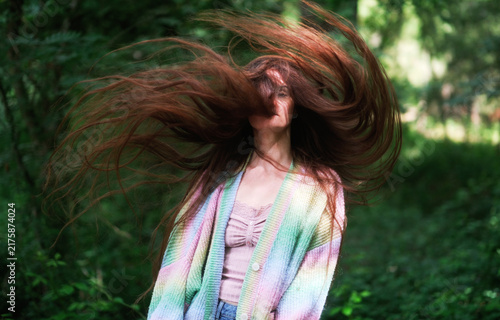 Fotografía Young brunette woman swings her exceptionally long hair through the air in a gre