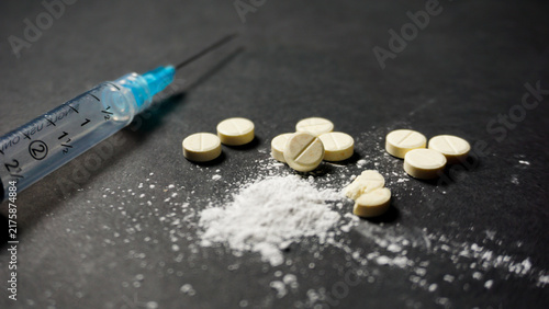 Canvastavla White illegal drugs in powder and pill form with a syringe on black background