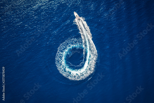Foto Overhead view of a motor boat forming a circle over the blue sea and driving awa