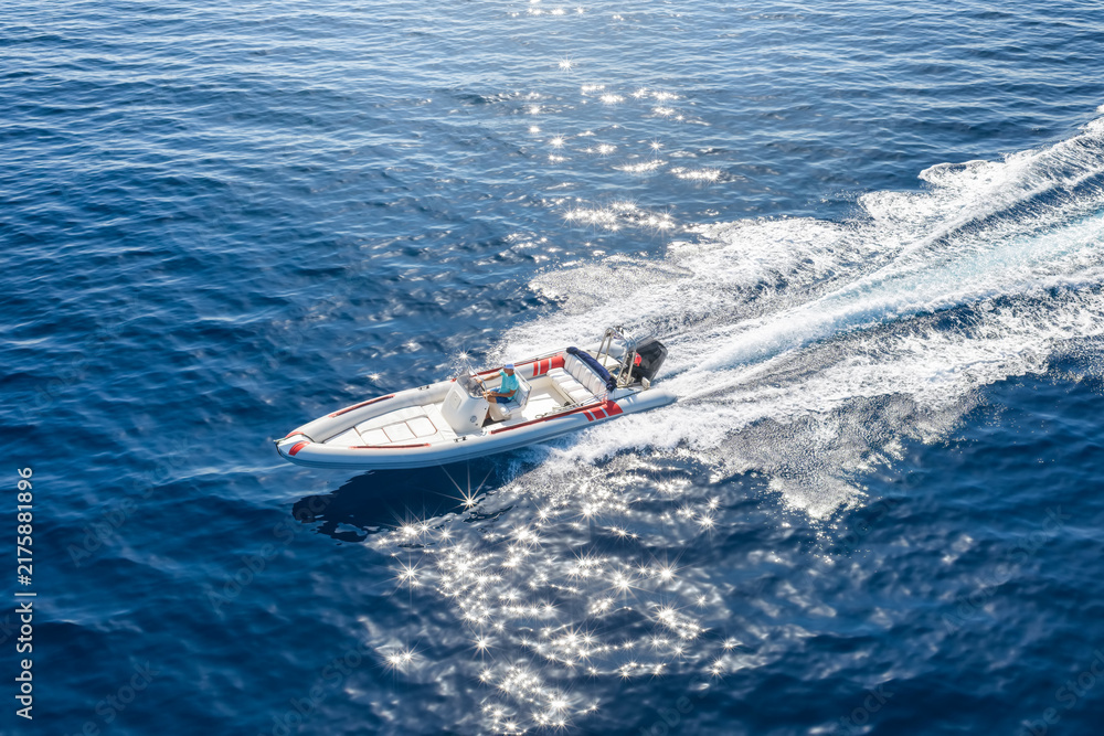 Obraz premium Aerial top view of a RIB motorboat with outboard engine cruising with high speed over the ocean