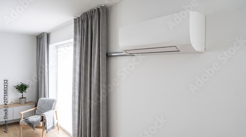 Modern white wallmounted air conditioner unit in a bright minimalist living room interior