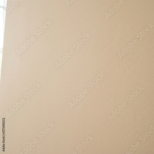 A plain, smooth, light beige wall surface is illuminated by natural soft light.