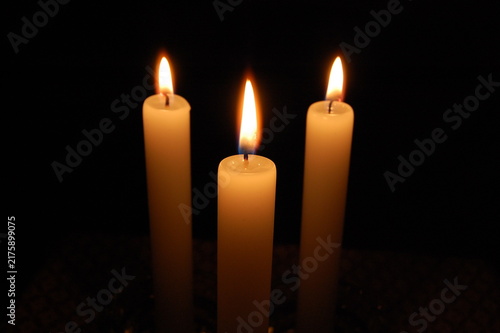 Obraz na płótnie Close-up of a burning candle with a bright glowing flame reflected in a dark surface, isolated against a black background