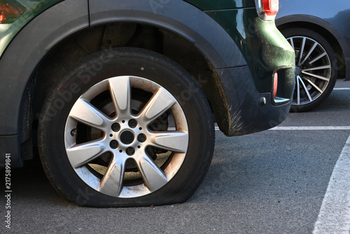 Rear wheel with flat tire on parked car.