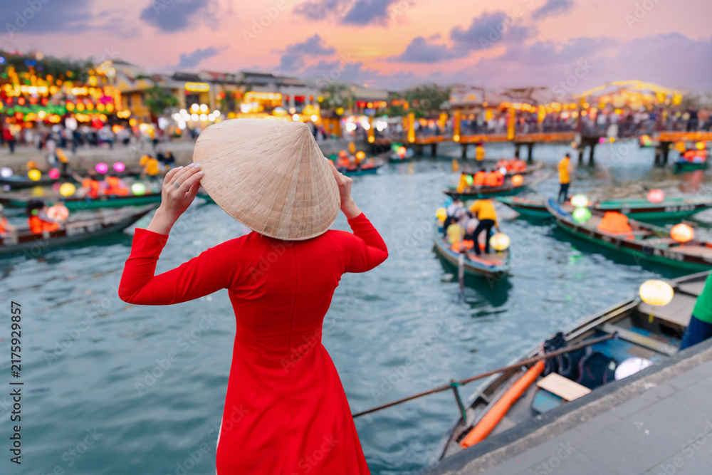 Obraz premium Young asian woman in red dress overlooking lantern boats in hoi an at sunset