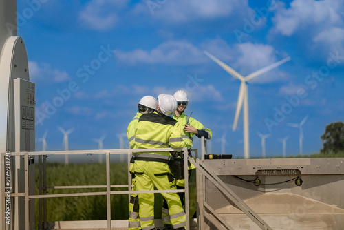 Foto Curved white turbine tower fills the left edge as two technicians on a small ste