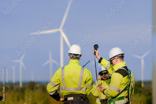 Obraz na płótnie Crew of three take a wind reading beneath a turning rotor, one man holding the m