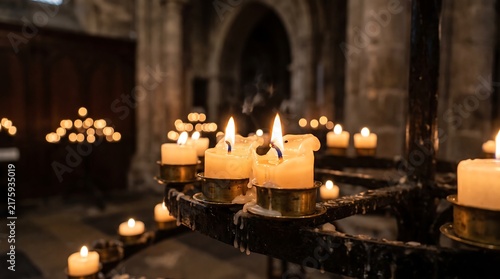 Burning prayer candles glowing with warm light inside a historical stone cathedral