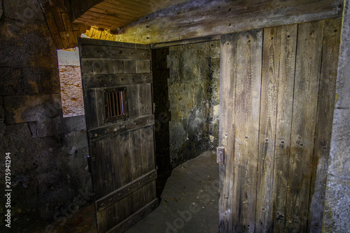 Bild auf Leinwand Heavy wooden prison cell door with small barred hatch in a dark dungeon