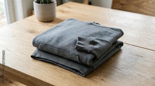 Neatly folded gray hoodie sweatshirt on a light wooden table