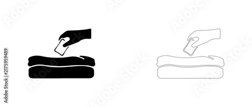 Hand placing sachet on folded clothes vector icon filled and outline, wardrobe fragrance packet and moth protection symbol.