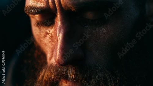 Close-up portrait of a weathered man with a long beard and intense gaze