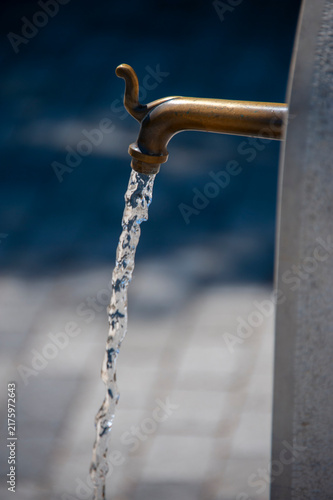 Canvas Print Bronze faucet pouring fresh water into a fountain