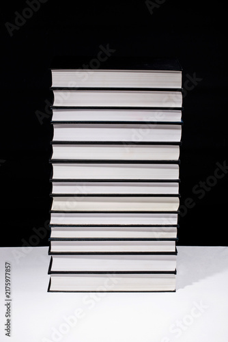 Cuadro en lienzo A tall stack of large books on a black background