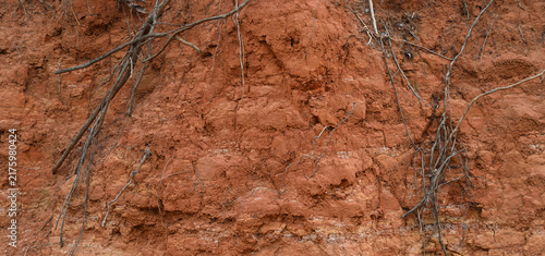 Obraz na płótnie A close‑up view of a roadside red clay dirt excavated slope with uneven natural