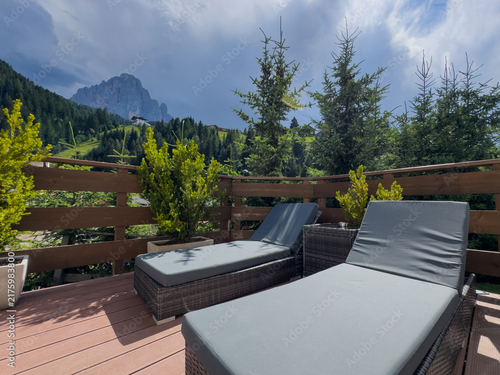 Obraz premium Modern patio furniture with sofa. Overlooks rich green mountain landscape. Sunny day bright airy atmosphere. Perfect outdoor living space