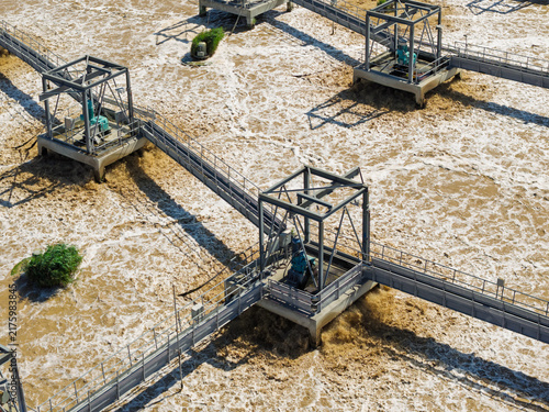 Fotografie Industrial Wastewater Treatment Facility With Churning Brown Water During a Sunn