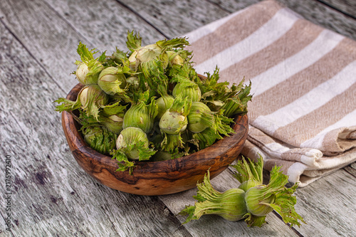 Konstfotografi Bowl of fresh green hazelnuts or cobnuts on rustic wooden table