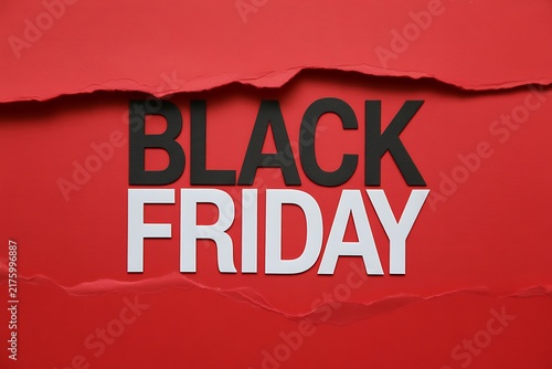 Black friday text revealed behind a torn red paper background for retail shopping sale promotion advertisement