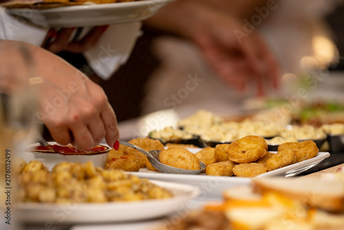 Hand scooping a fried bite from a catering buffet with a serving spoon, capturing food service in action and highlighting event catering, hospitality, and communal dining.