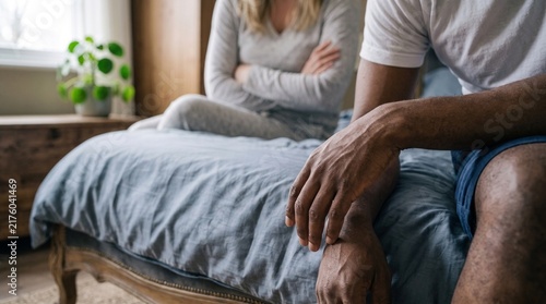 A couple sitting on the bed having a serious conversation about their relationship problems.