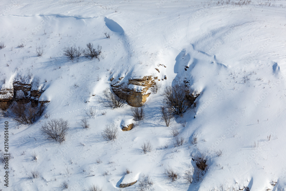 Naklejka premium Snow blankets rugged terrain with exposed rock outcrops