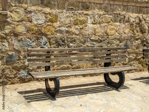 Fotografía Weathered wooden bench with curved black metal supports sits gracefully on light
