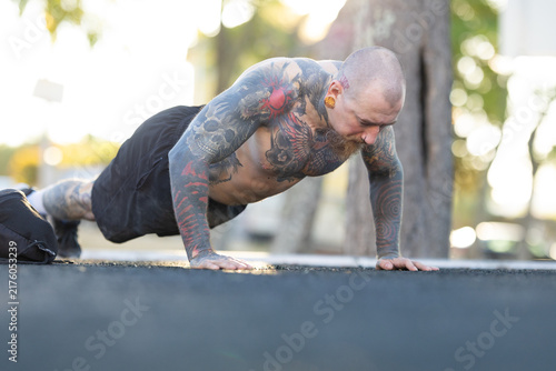 Fotografía Man doing push-ups in a park during morning hours with clear skies
