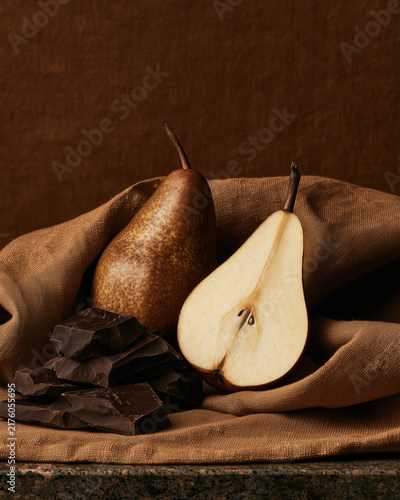 Pear and dark chocolate still life on brown fabric