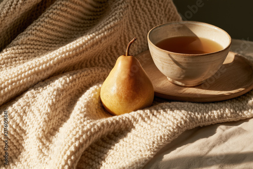Cozy tea and pear still life with knitted blanket