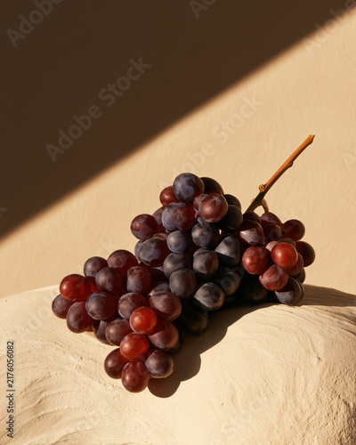 Red grape cluster in warm sunlight with dramatic shadow