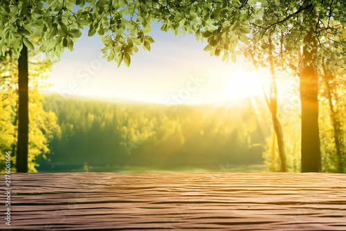 Wooden table top with blurred sunny forest and green leaves
