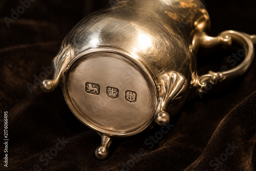 Antique silver cream jug with hallmark stamps on dark velvet, craftsmanship and heritage concept