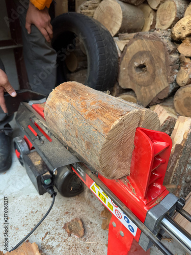Fotografía A red hydraulic log splitter clamping a large piece of firewood in a rustic workshop
