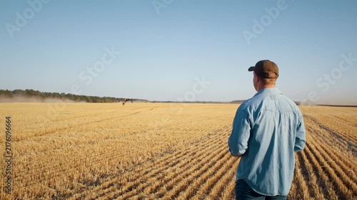 Farmer holds tablet and turns to look at flying stork over field