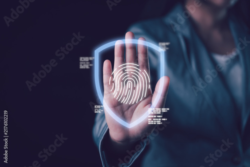 Businesswoman making a stop hand gesture with a glowing digital shield and fingerprint icon overlay