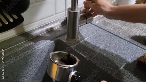 Washing professional coffee tools after brewing espresso in a cafe, equipment care, barista workplace hygiene, maintenance process.