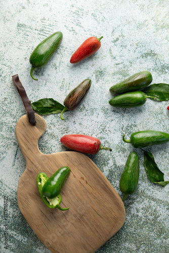 Fotografía Green and red jalapeno chili peppers on green and white surface.