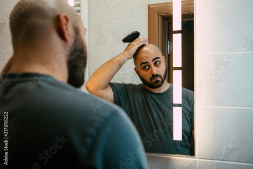Foto A young man shaving his head with an electric razor for head shaving in a bathroom