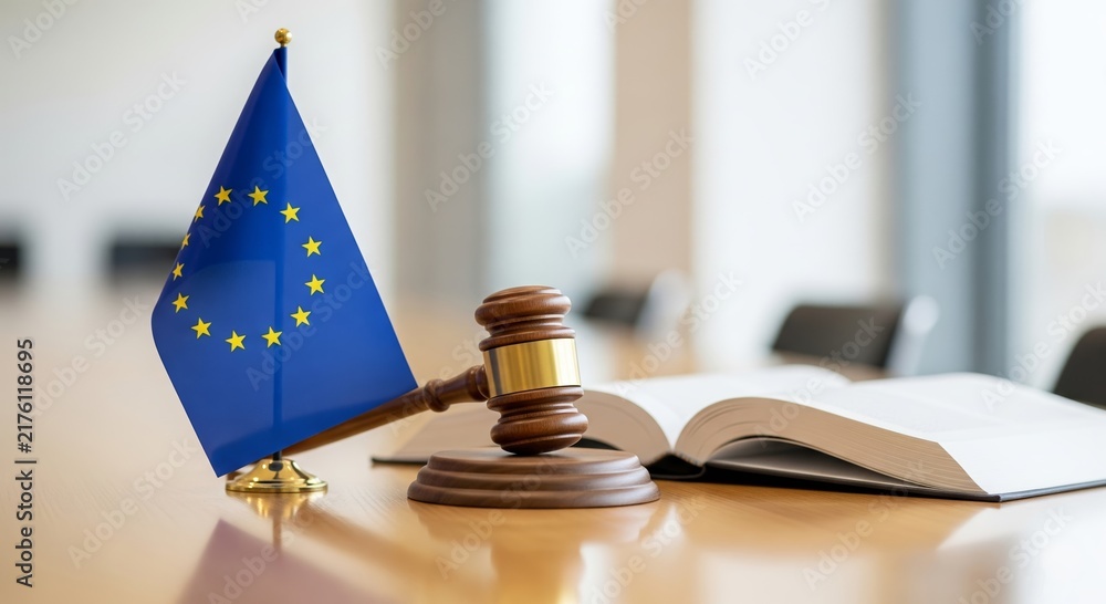 Obraz premium European union flag with judge gavel and open law book on wooden desk in bright office. EU legislation and justice concept. European court legal system and regulation