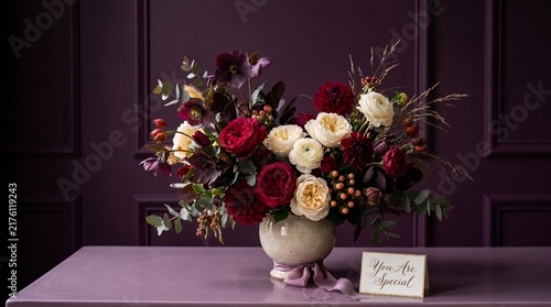 Moody burgundy and cream floral arrangement on dark purple background