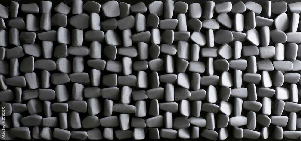 Fototapeta premium Black stones arranged in a grid pattern on a flat surface indoors