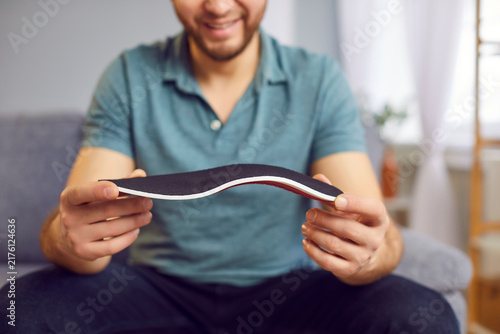 Canvastavla Man is holding an orthotic insole in hands, maintaining foot health, especially for individuals with flat feet