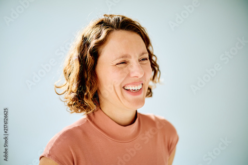 Картината върху платно Woman with curly hair winking and laughing, expressing pure joy and happiness